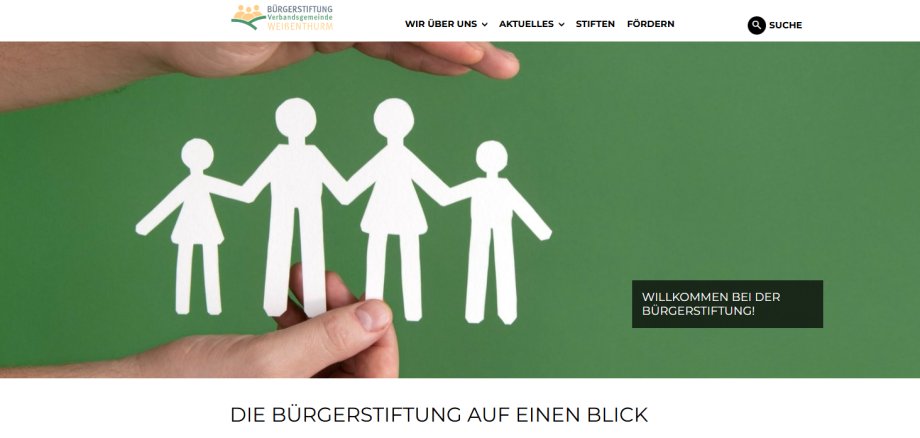 Zu sehen ist die Startseite der Internetseite mit aus Papier ausgeschnittenen, weißen Personenumrissen vor einem grünen Hintergrund, die von zwei Händen gehalten werden. 